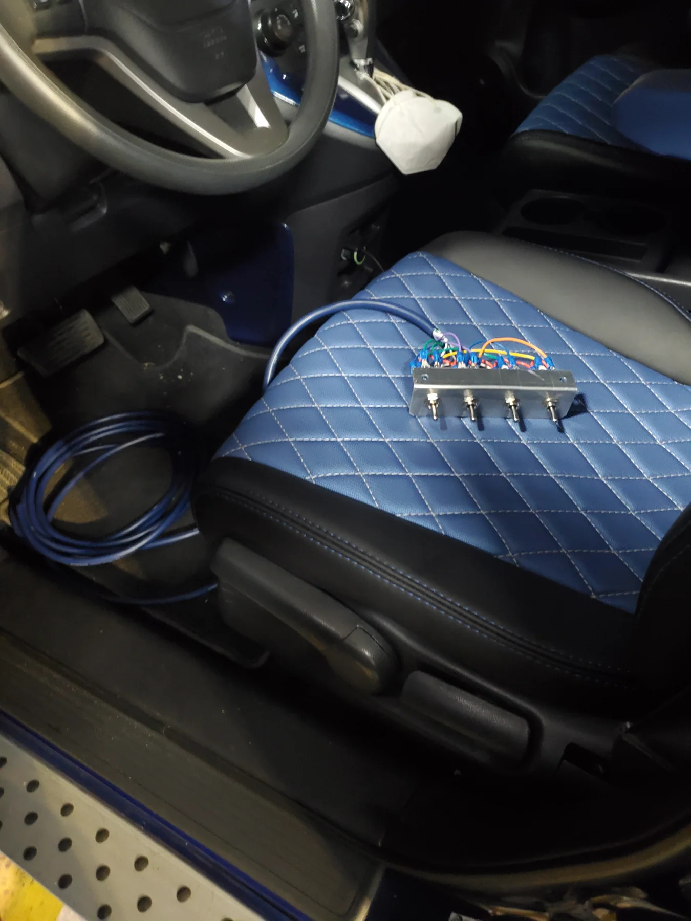 Custom switch wiring staged on a blue quilted front seat